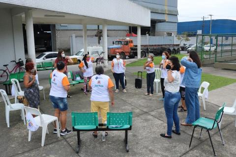 pessoas em pé fazem atividade fisica em frente a unidade de saude #paratodosverem
