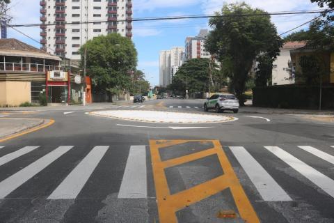 faixa de segurança de pedestres em primeiro plano, rotatória ao fundo e carro passando. #paratodosverem