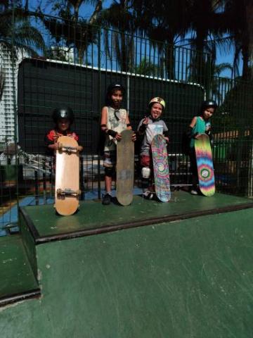 Quatro crianças seguram skate #paratodosverem