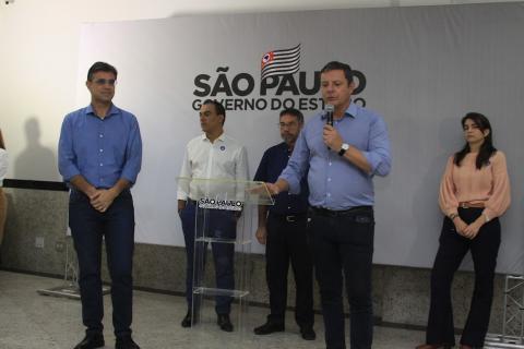 prefeito fala ao microfone ao ladodo governador. Ao fundo, três pessoas em pé. Na parede há um painel onde se lê São Paulo - governo do Estado. #paratodosverem