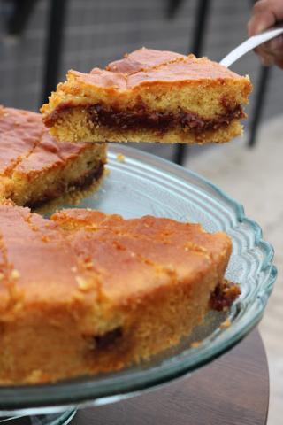 bolo está cortado em fatias sobre um prato. Uma mão segura uma pá com uma das fatias. #paratodosverem