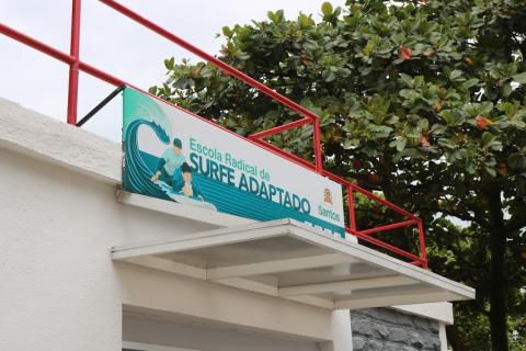 pedaço de fachada da escola de surfe adaptado, com placa. #paratodosverem