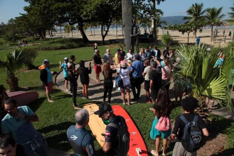 turma se reúne em frente a estátua do surfista no jardim da orla. #paratodosverem