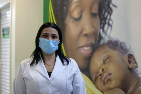 enfermeira posa na frente de painel com  foto de mãe e filho #paratodosverem