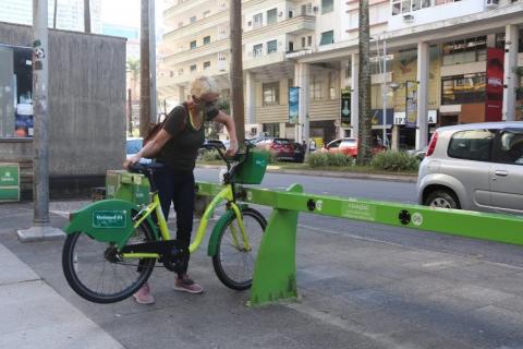mulher retira bicicleta de estação #paratodosverem