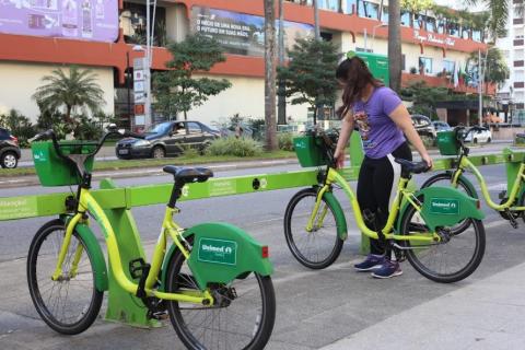 mulher retira bicicleta de estação #paratodosverem
