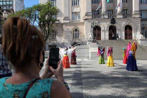 ciganas dançam na praça, enquanto mulher fotografa #paratodosverem