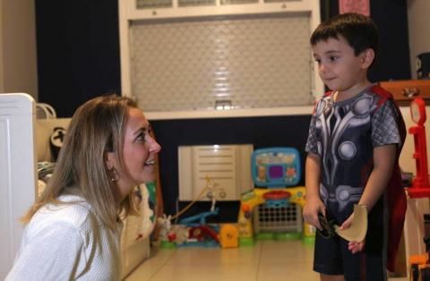 #pracegover no quarto de casa, Tatiana, sentada ao chão, olha para Gael, que está em pé