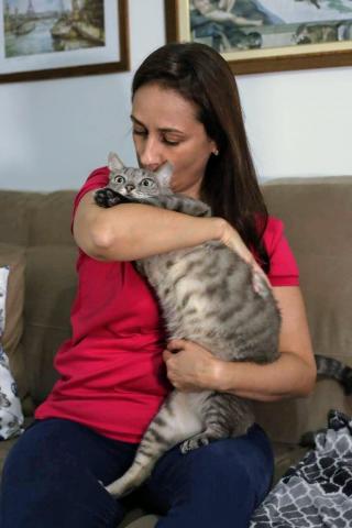 #pracegover no sofá de casa, Maria Estela beija o gato Davi