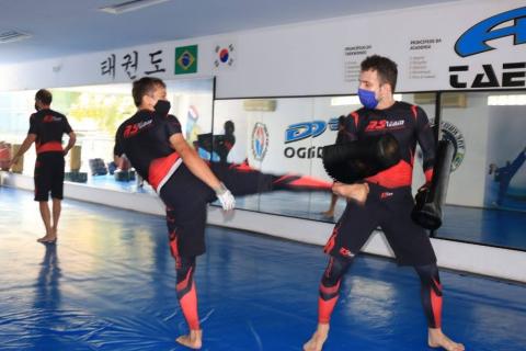 atleta treina chutes em colega que tem protetores nos braços. #paratodosverem 