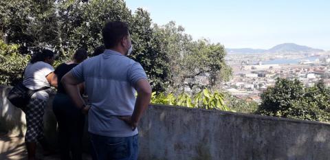 Pessoas observam a vista áerea de Santos do morro #paratodosverem