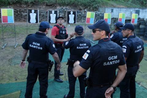 grupo de guardas uniformizados está diante de alvos. Eles conversam e prestam atenção em instrutor. #paratodosverem