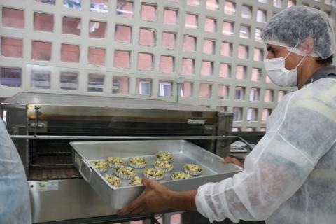 assadeira com mini tortas é colocada dentro de formo por uma pessoa. #paratodosverem