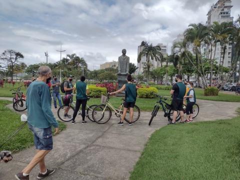 Ciclistas desmontam da bike para observar monumento a Bartholomeu de Gusmão. #paratodosverem