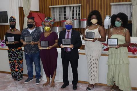 Pessoas posam para foto segurando troféu 