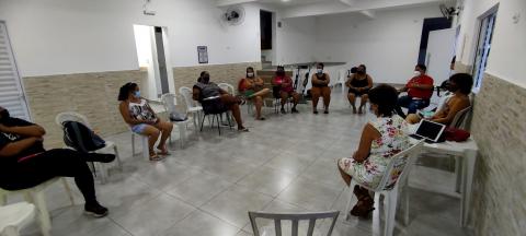 reunião em salão, com pessoas sentadas em cadeiras em formato de roda. Elas conversam. #paratodosverem