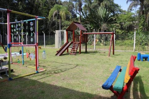 palyground com brinquedos e cercado por área verde #paratodosverem