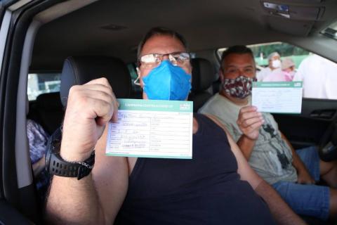 Dentro de veículo, homem exibe comprovante de vacinação. #paratodosverem