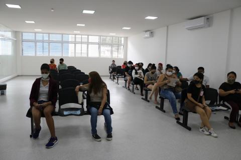 salão de policlínica com várias pessoas sentadas. #paratodosverem