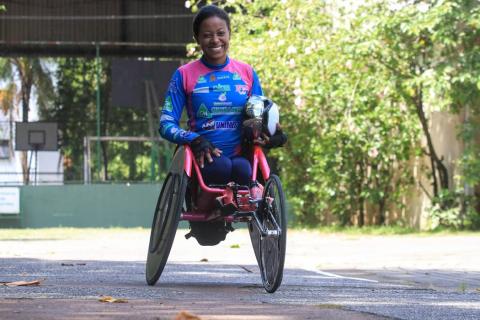 Atleta ao lado da cadeira de rodas posa para foto #paratodosverem