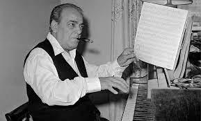 vila lobos ao piano com a mão esquerda em uma partitura. #paratodosverem