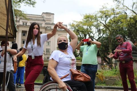 Duas mulheres em movimento de dança com cadeira de rodas. #paratodosverem