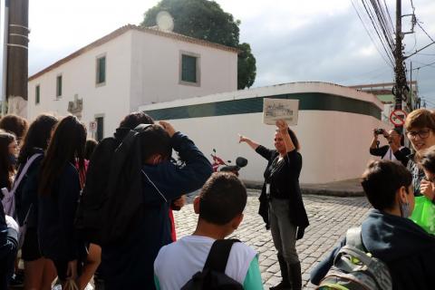 crianças de costas para a foto observam a fachada da casa do trem bélico. #paratodosverem