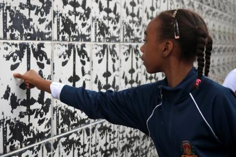 menina passa a mão em azulejo de parede no Outeiro de Santa Catarina