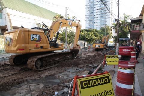 Máquinas operando em rua. Placas avisam sobre cuidados para circulação. #paratodosverem