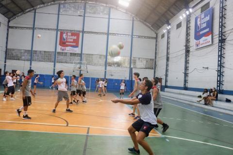 alunos praticam fundamentos do vôlei em quadra. Há grande movimentação. #paratodosverem