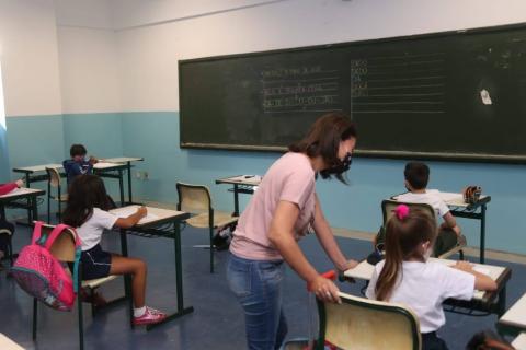 professora está ao lado de aluna. Todos os estudantes estão sentados distantes uns dos outros. #partodosverem