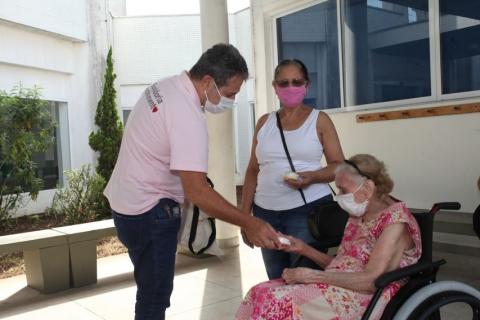 voluntário entrega copo a senhora em cadeira de rodas  #paratodosverem
