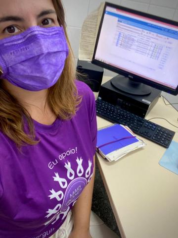 médica veste roxo ao lado de computador #paratodosverem