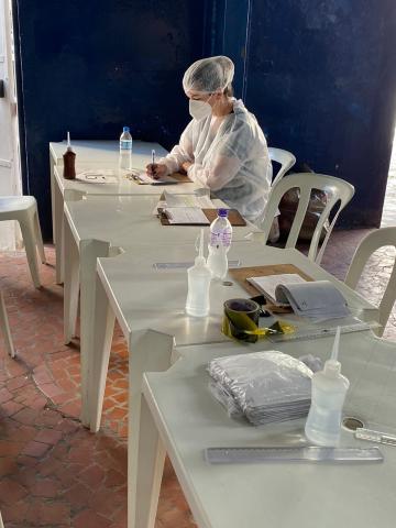 voluntária esta sentada e faz anotações na mesa #paratodosverem