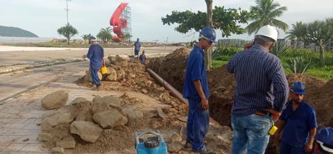 homens trabalham em obra do lado do jardim da praia com grande vala aberta e encanamento dentro #paratodosverem