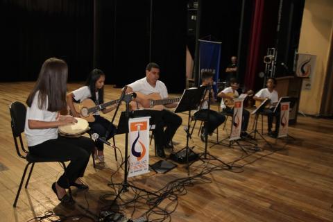 crianças tocam instrumentos no palco #paratodosverem