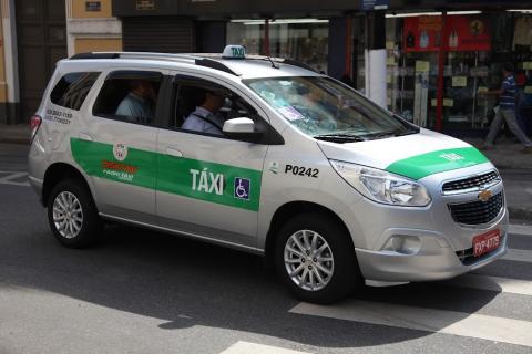 carro adesivado como táxi passando por cima de faixa de pedestres #paratodosverem