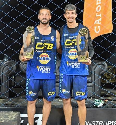 dois atletas segurando troféu #paratodosverem
