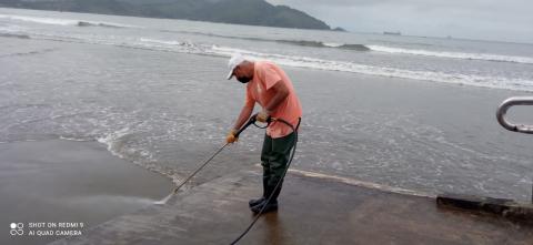 Homem limpa passarela na praia com jato de água #paratodosverem