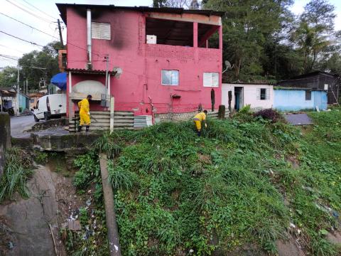 Trabalhadores realizam serviço de limpeza na encosta do morro. #paratodosverem