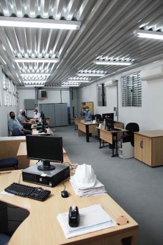 sala administrativa, com várias mesas e desktops. #paratodosverem