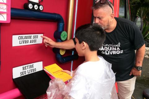 profissional ajuda criança a usar a máquina #paratodosverem