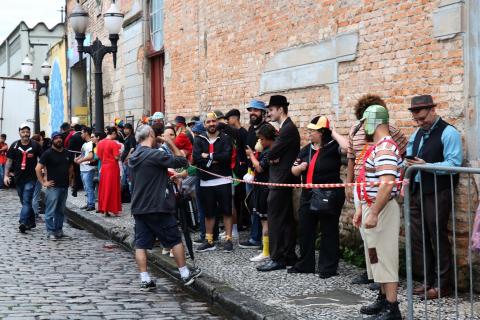 Pessoas vestidas como personagens do Chaves fazem fila na rua. #Pracegover