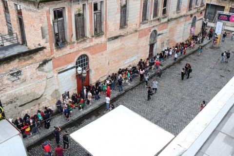 Fila na rua ao lado de prédio histórico. #Pracegover