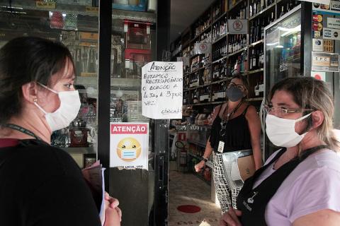 Agente está na entrada de loja observando duas mulheres à frente. #Paratodosverem