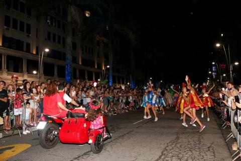 #pracegover Centenas de pessoas os dois lados da via assistem a mulheres dançando