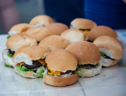 Mesa contém 13 pães com hambúrger, queijo e alface 