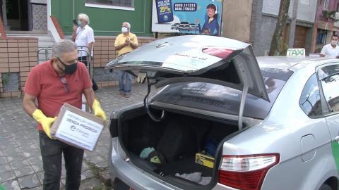 Homem coloca caixa em bagageiro de carro. #paratodosverem