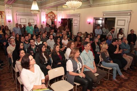 Pessoas na plateia durante evento de lançamento #pracegover