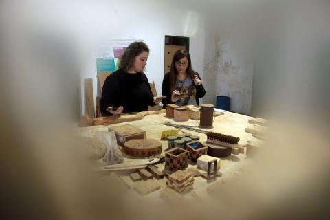 duas mulheres olham para peças de madeira #paratodosverem 